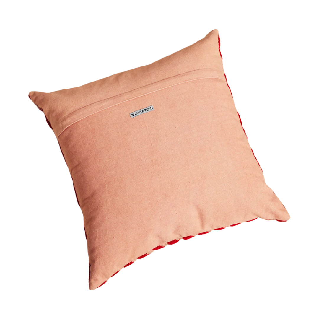 Peach-colored pillow with a brand logo on a white background