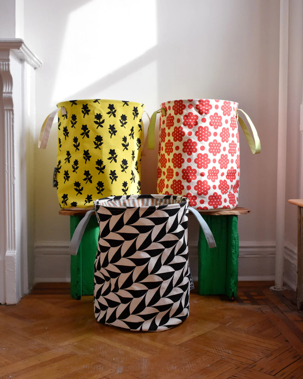 Three patterned storage baskets on a wooden floor.