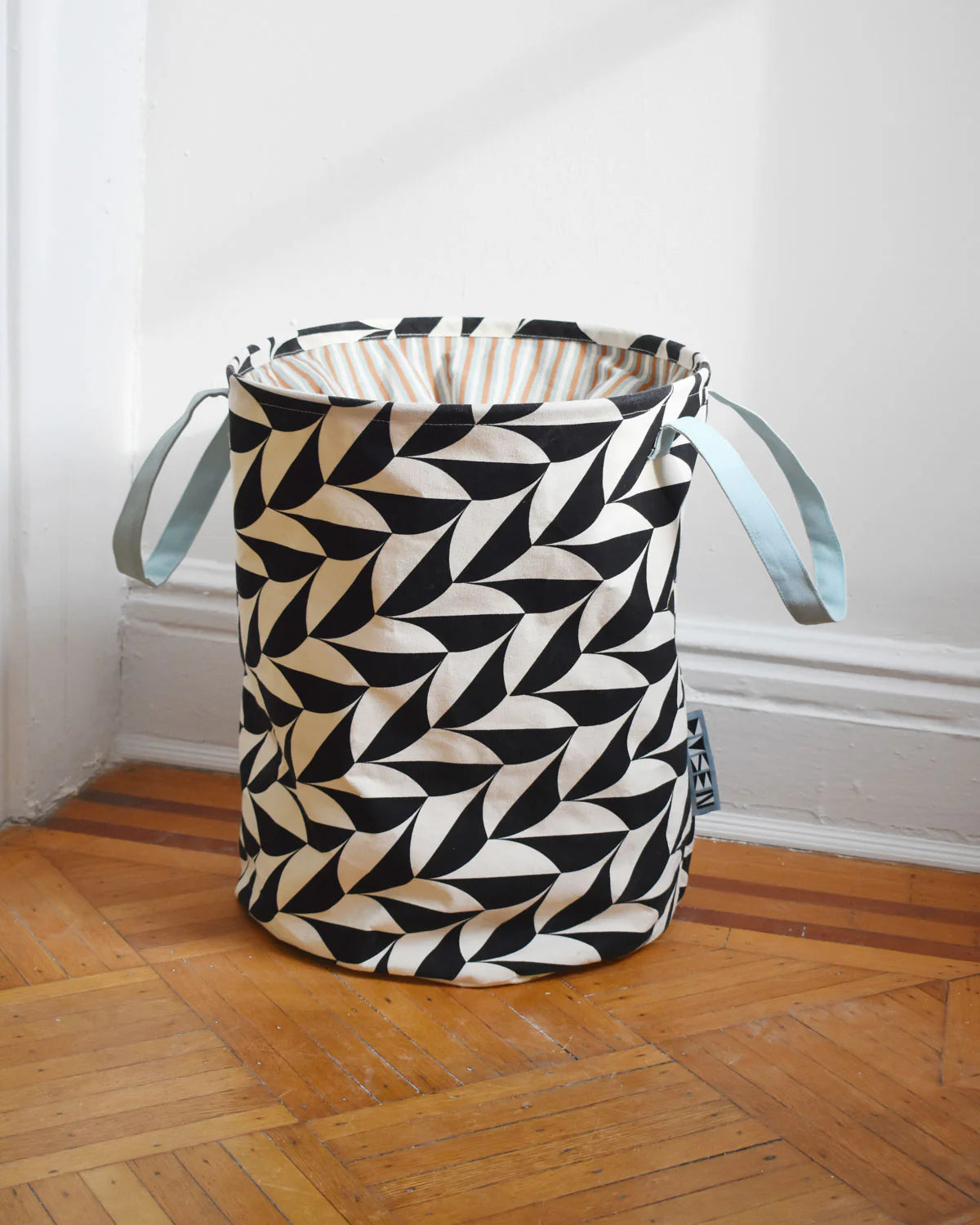 Black and white geometric patterned bag on a wooden floor with a white wall background